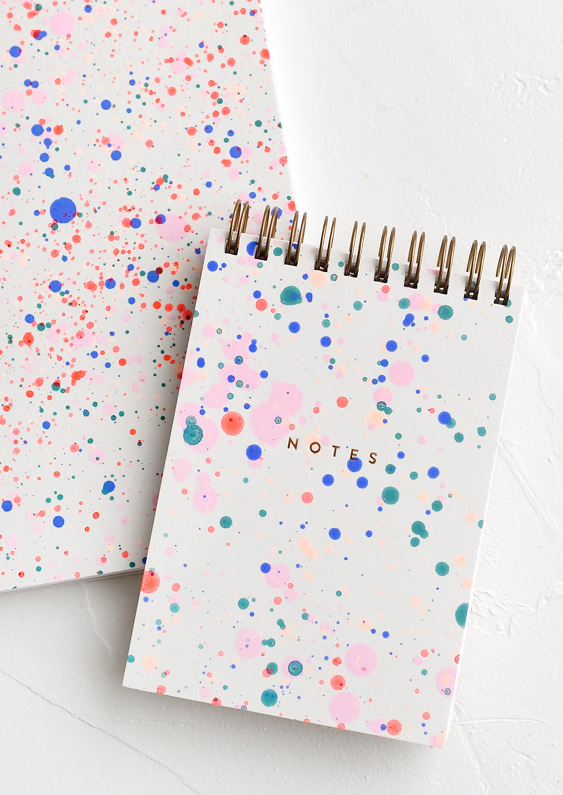 Spiral bound notepad with neon paint splatter cover.