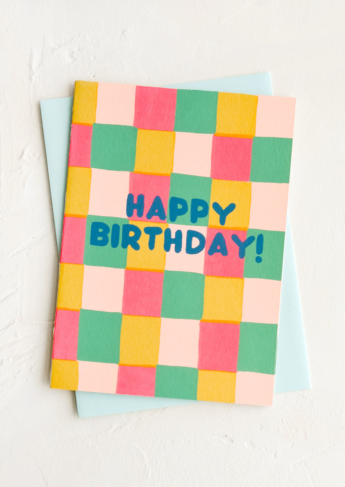 A greeting card with colorful square print background and "HAPPY BIRTHDAY!" text.