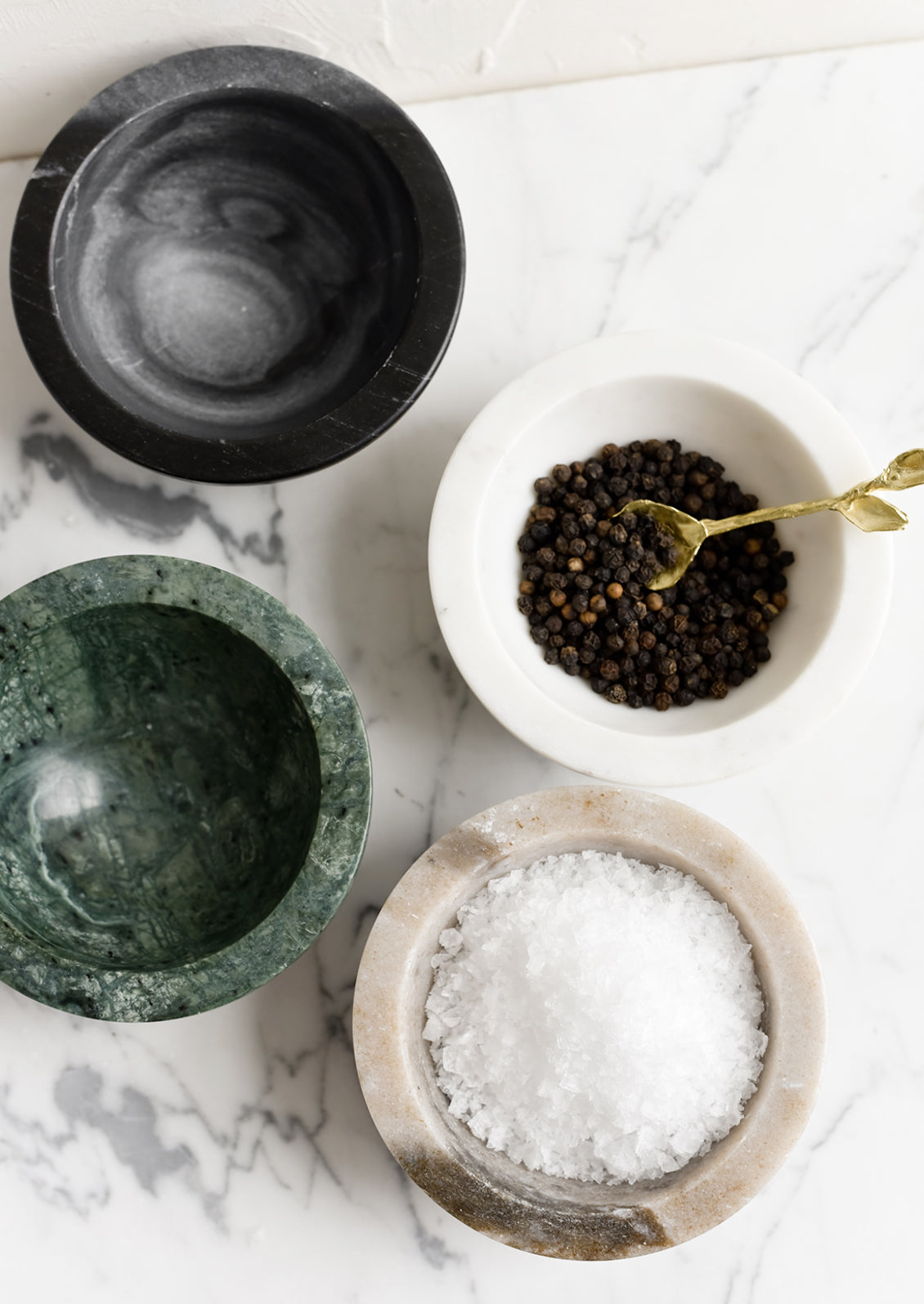 Marble bowls in assorted colors, some holding salt and pepper.