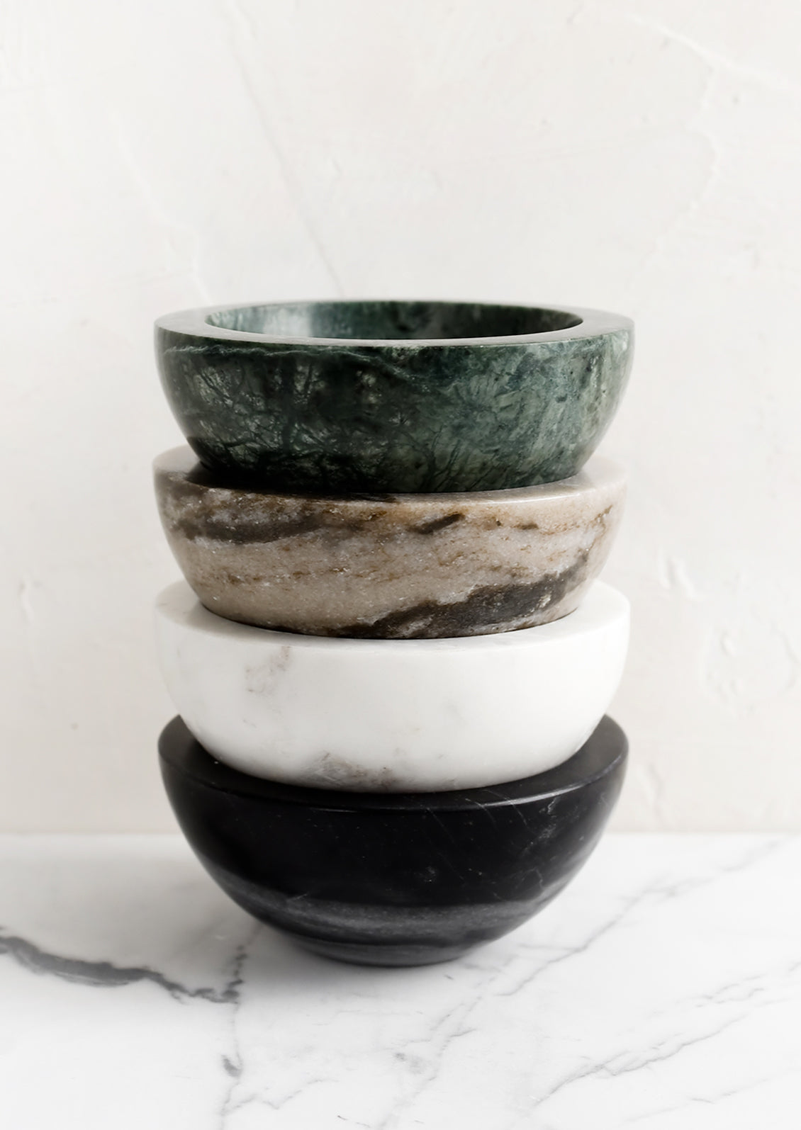 A stack of four small marble bowls in assorted colors.