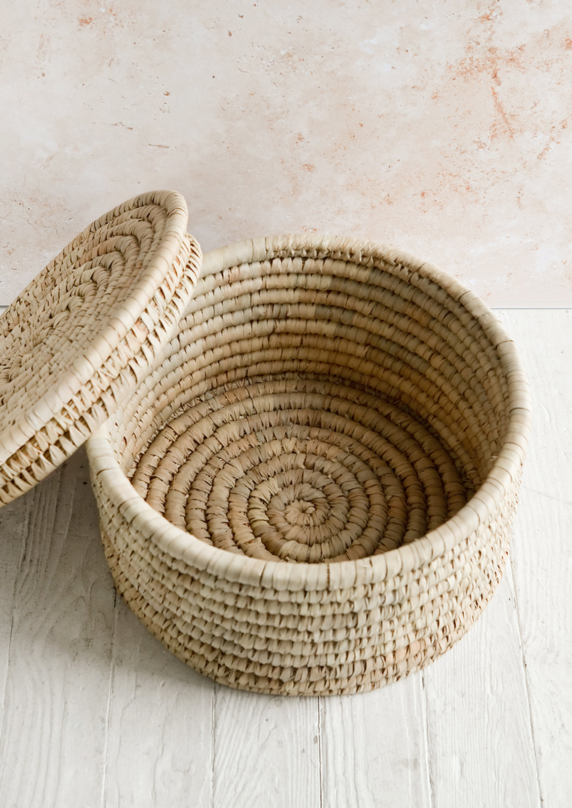 A round palm leaf storage basket with lid askew.