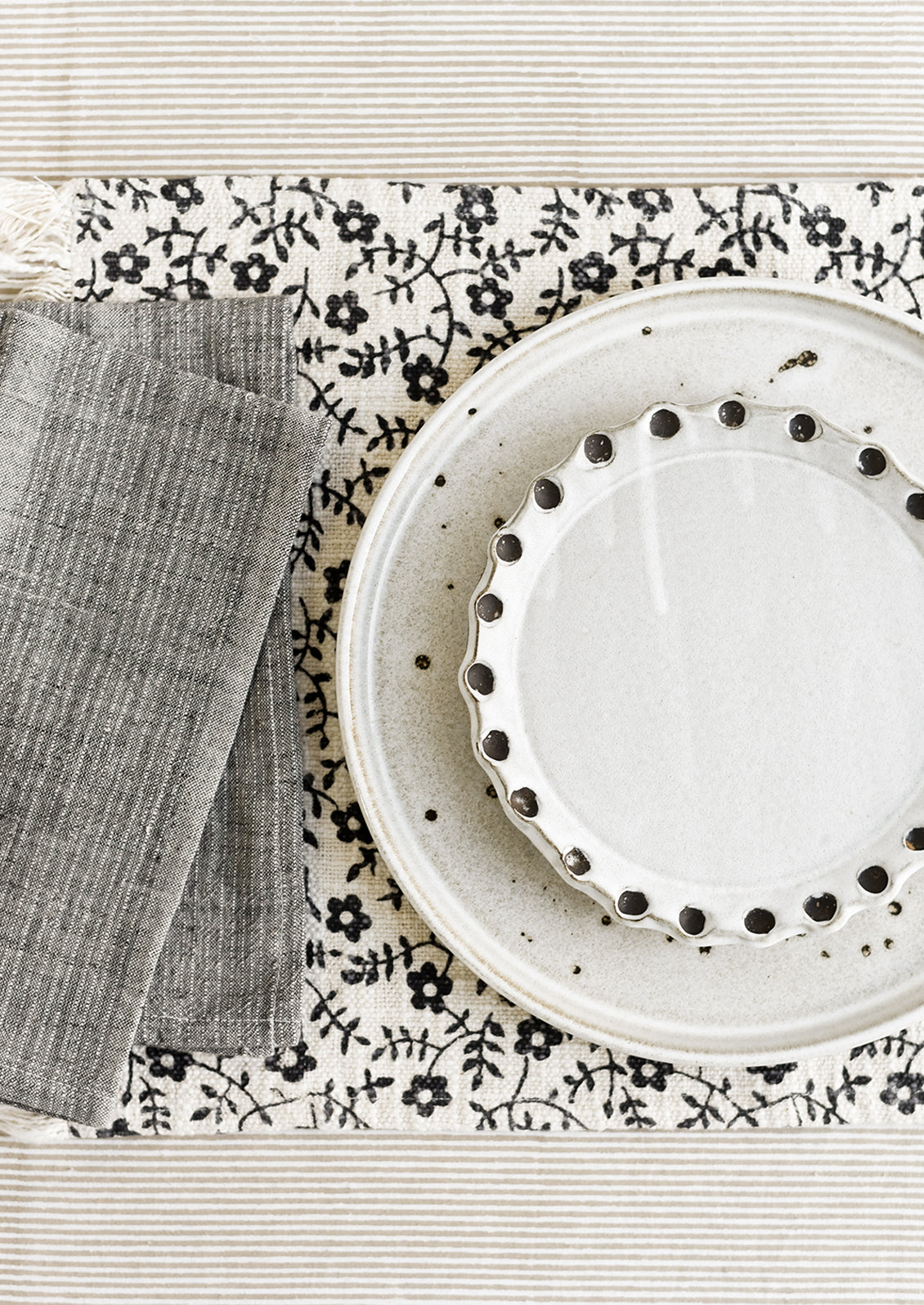 A neutral table setting with plates, napkins and placemat.