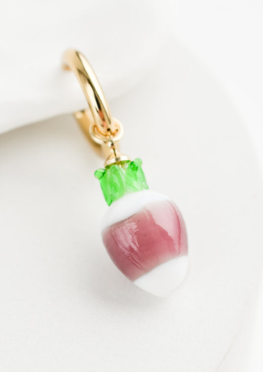 A single earring with glass turnip charm on gold huggie hoop.