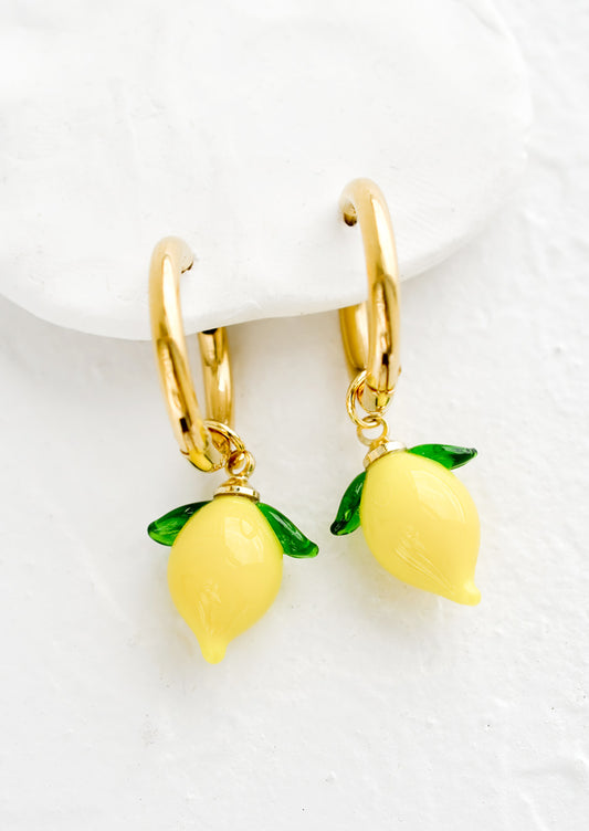 Gold huggie hoop earrings with glass lemon charms.