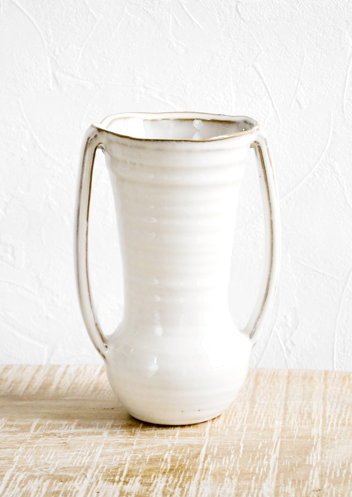 Glossy ceramic vase with hourglass silhouette and slim handles along sides