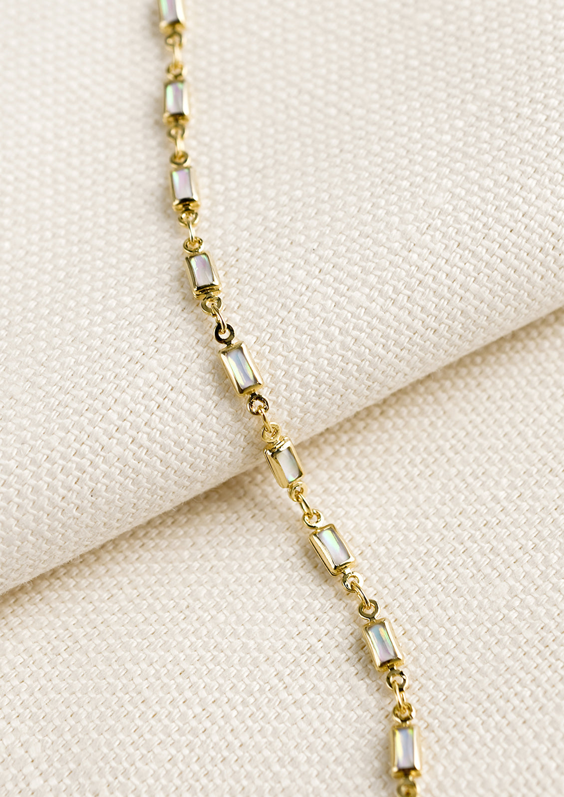 A gold bracelet with baguette shaped opals throughout.