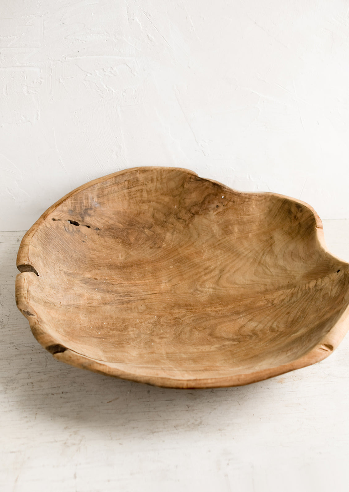 A large teak wood bowl with natural cracks and fissures.