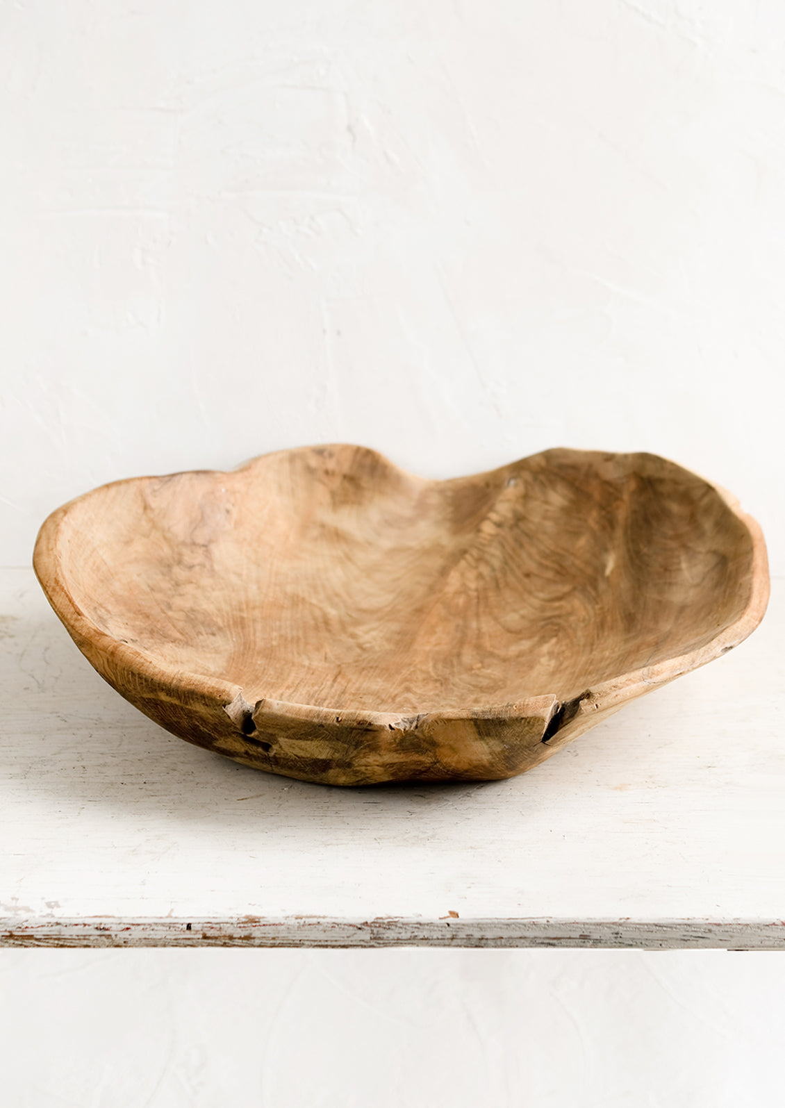 A large teak wood bowl with natural cracks and fissures.