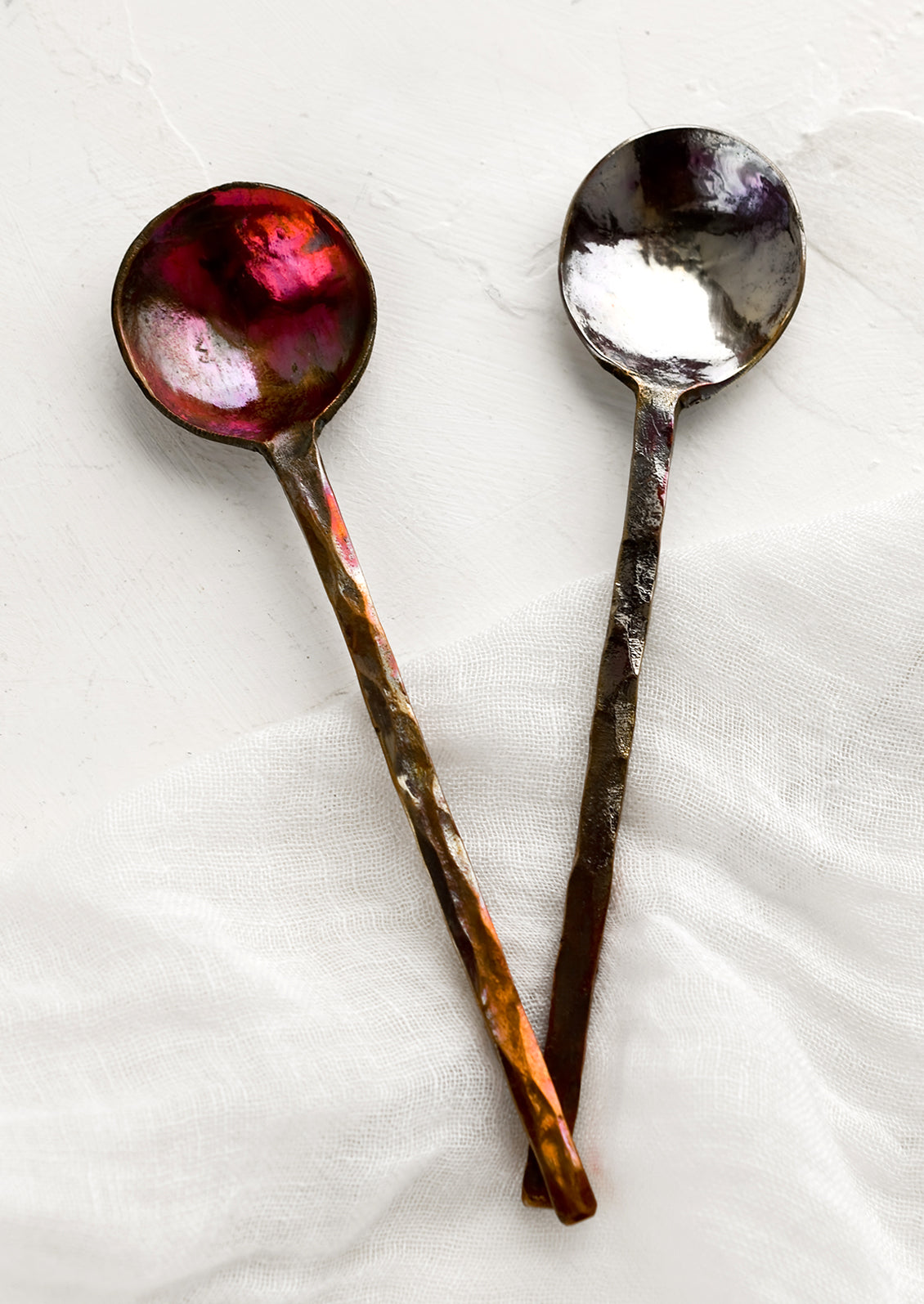 Oxidized metal spoons with varied oil-slick finish.