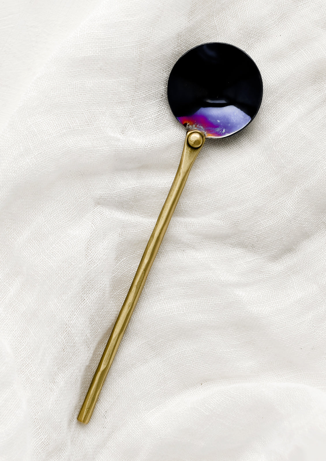 A metal spoon with brass handle and oil slick spoon.