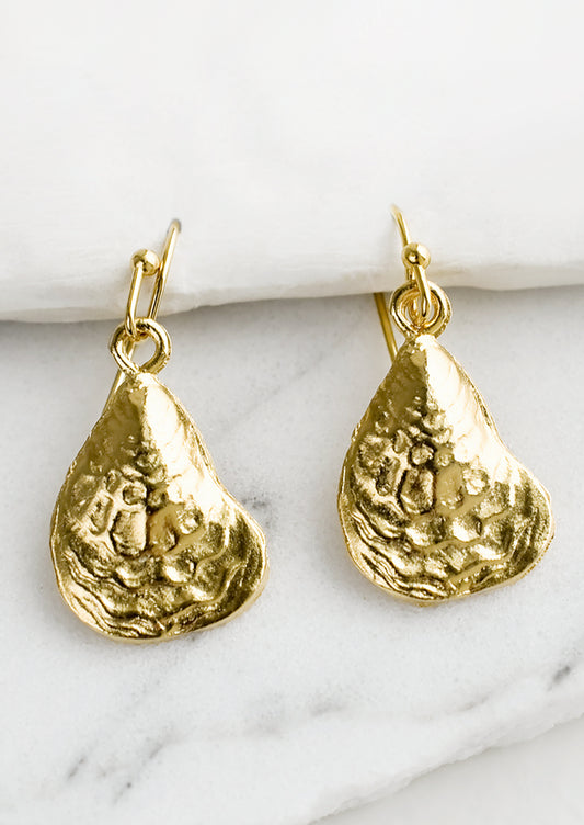 A pair of gold earrings in the shape of oyster shell.