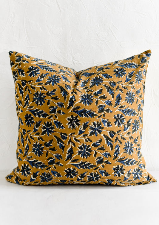 A block printed pillow with floral motif in blue and black on tan.
