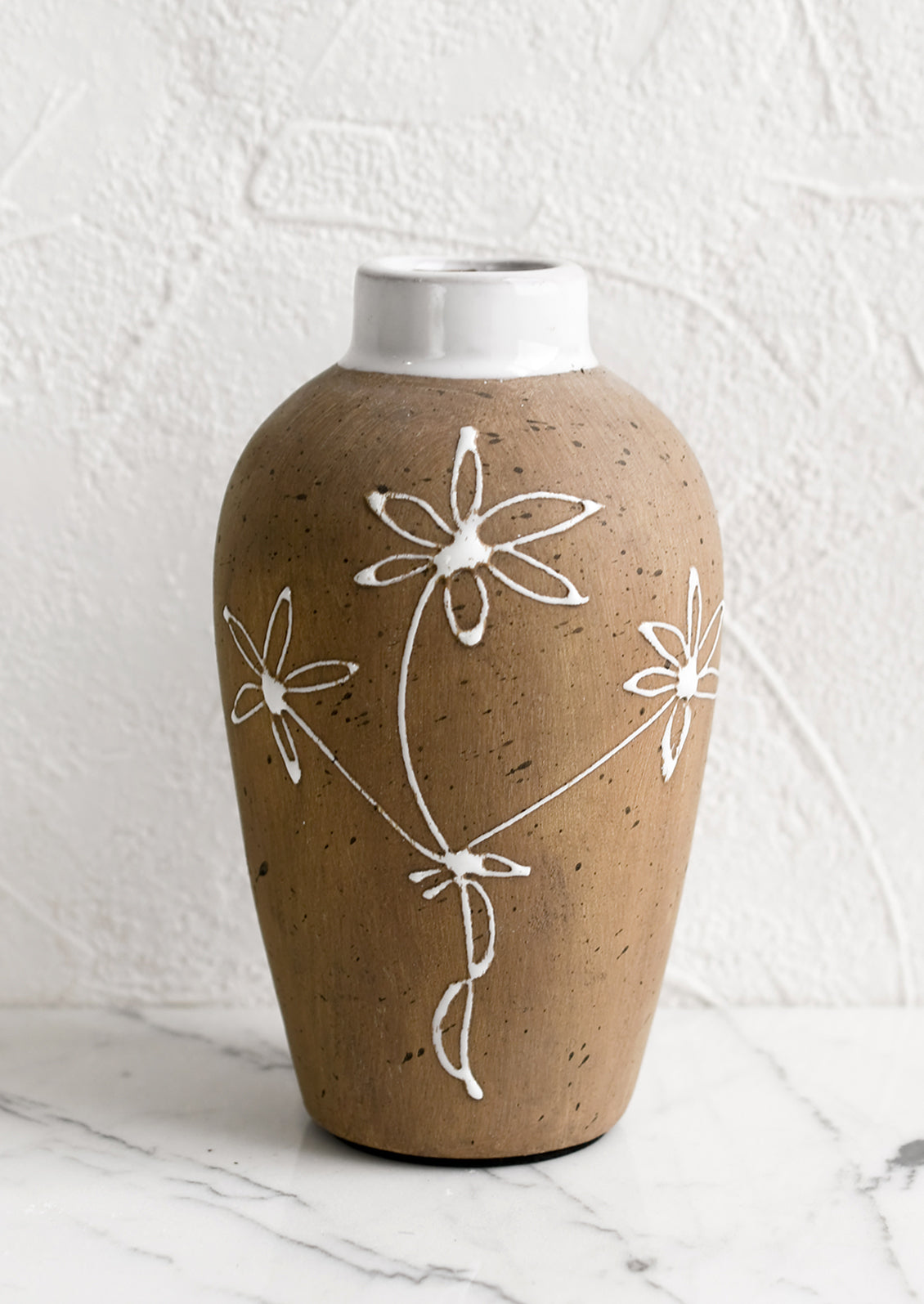 A brown clay vase with white floral sketch.