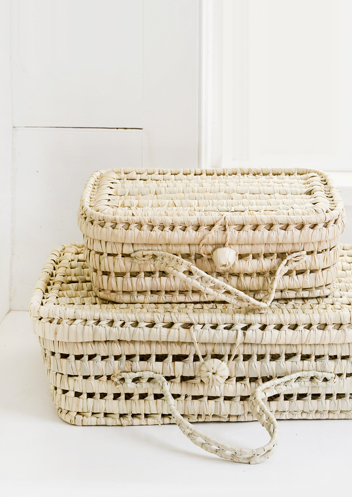 Baskets woven from natural palm leaf in suitcase shape, in small and large sizes.