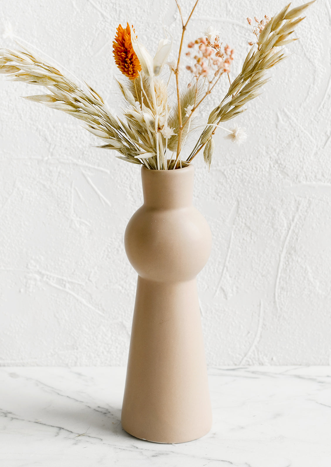 A blush ceramic bud vase with tapered shape.