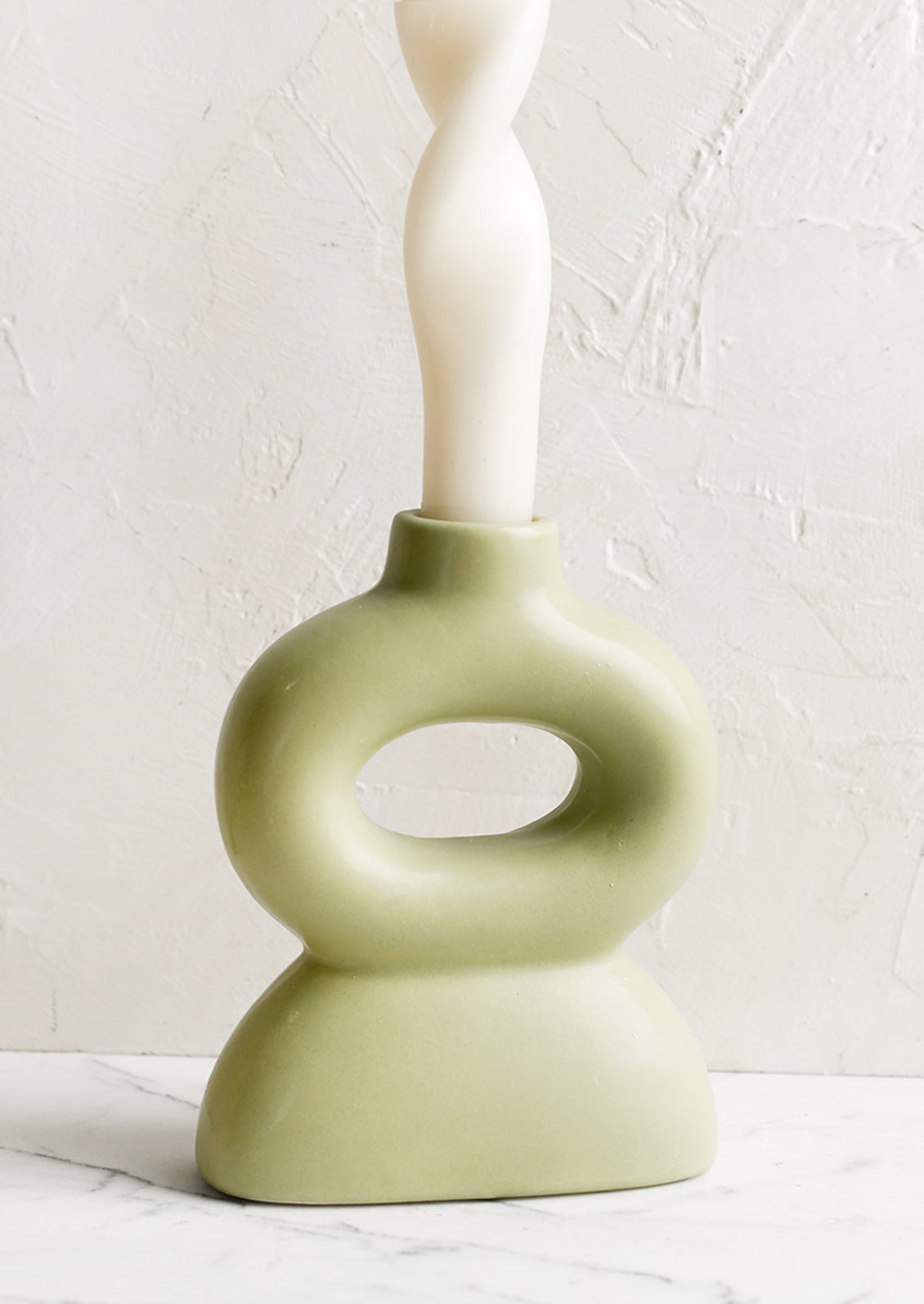 A curvy shaped taper candle holder in honeydew green.