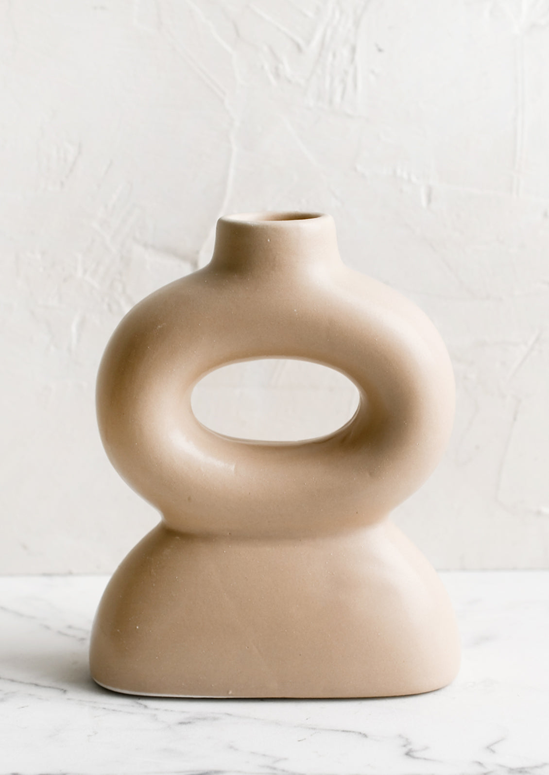 A curvy shaped taper candle holder in blush.