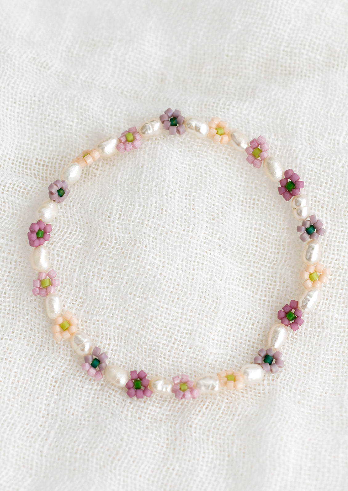 A beaded bracelet with white pearls and multicolor flowers.