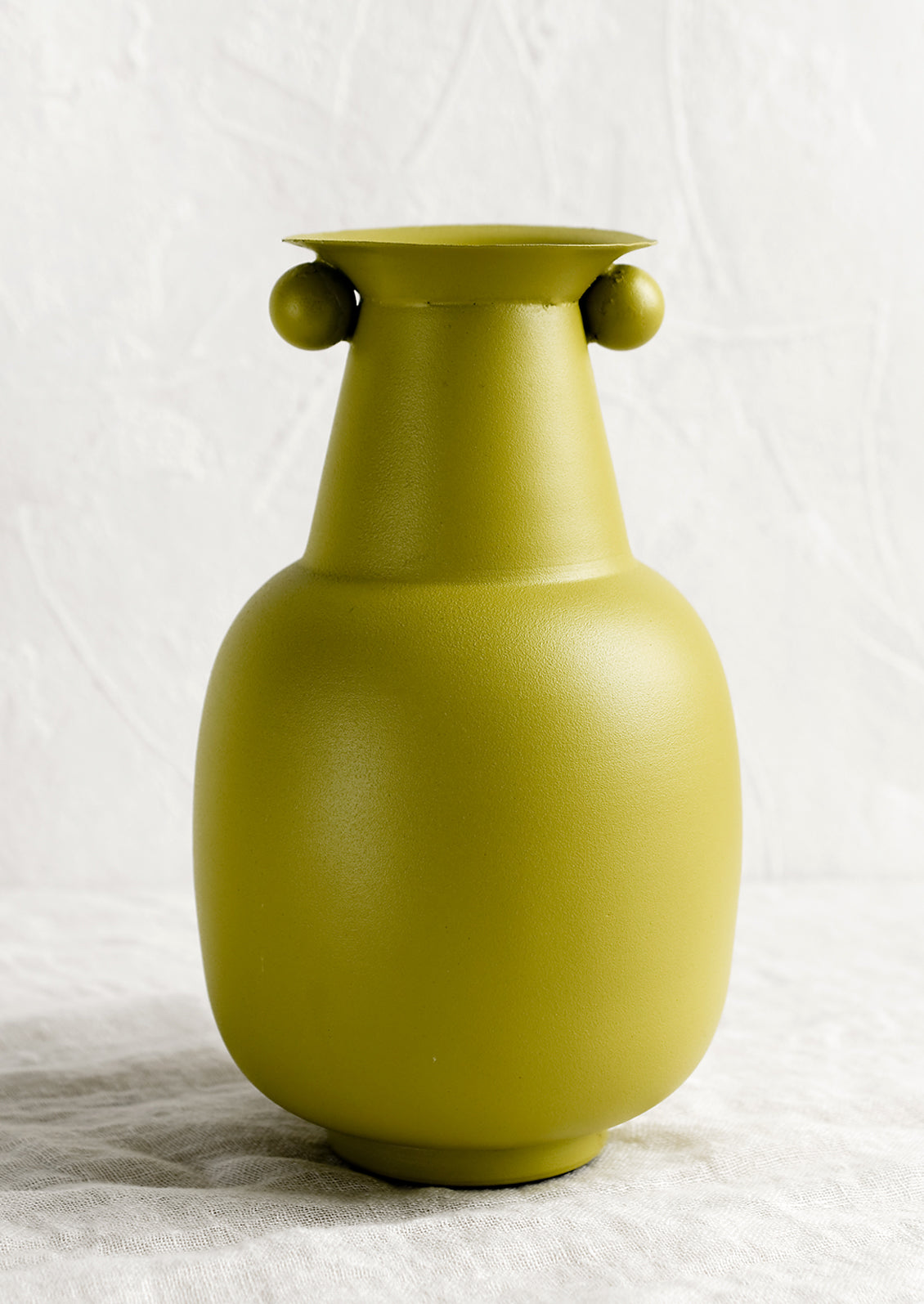 A lime green vase with round ball detailing at top.