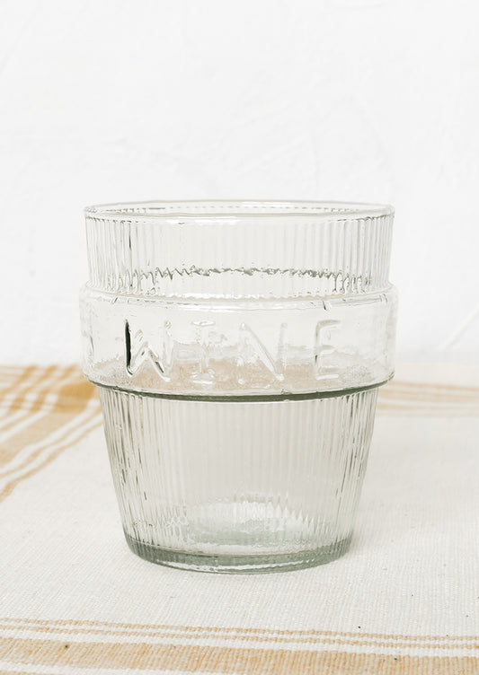 A short ribbed clear glass cup labeled "wine".