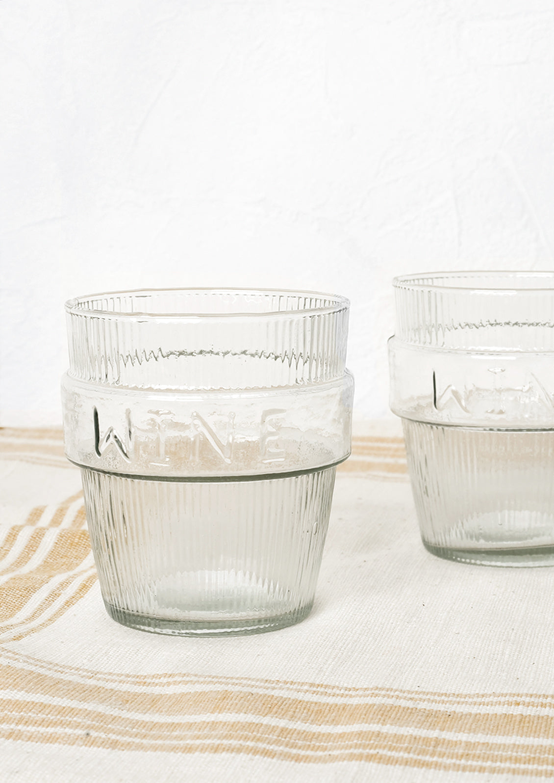 Two short ribbed clear glasses labeled "wine".