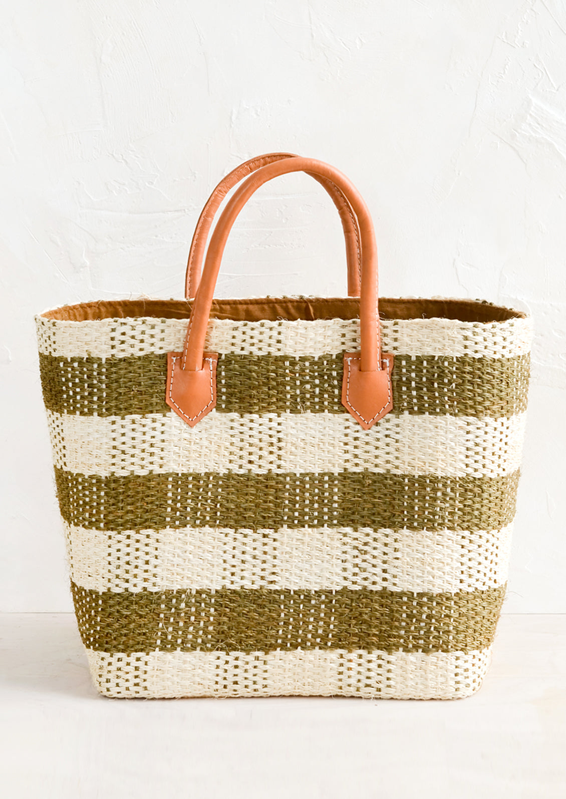 A raffia tote in olive and cream gingham with leather handle.