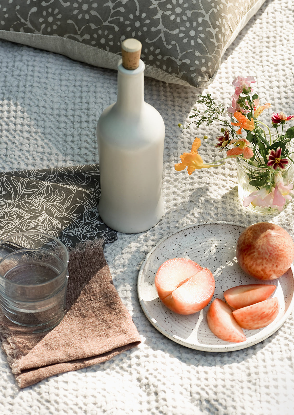 An outdoor picnic setting with fruit and wine.