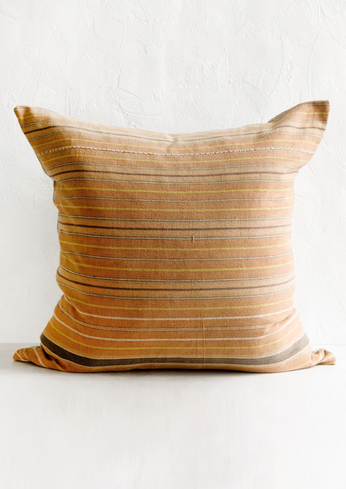 A throw pillow in clay stripe cotton fabric.