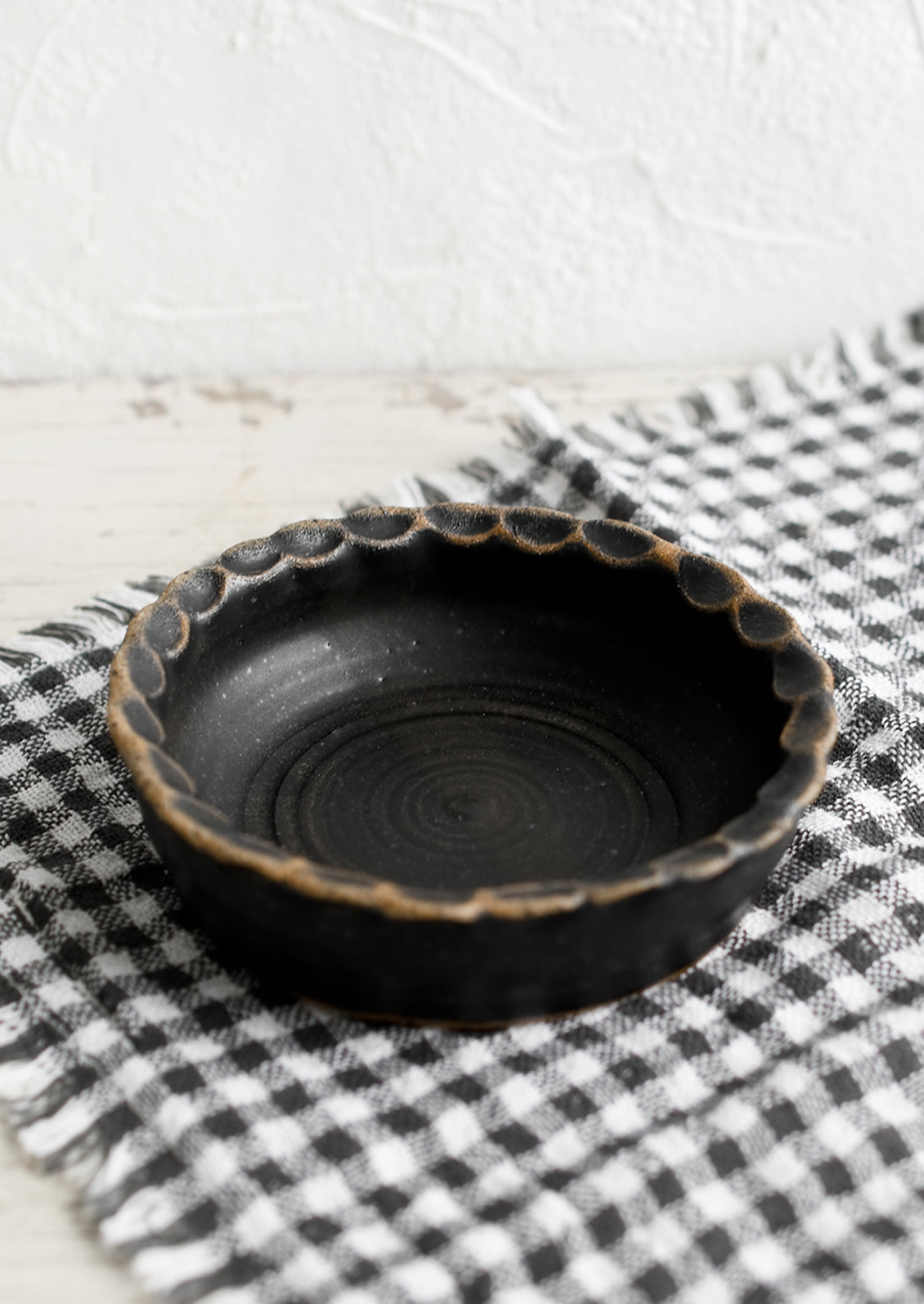 A small ceramic bowl with pinched rim in black glaze.