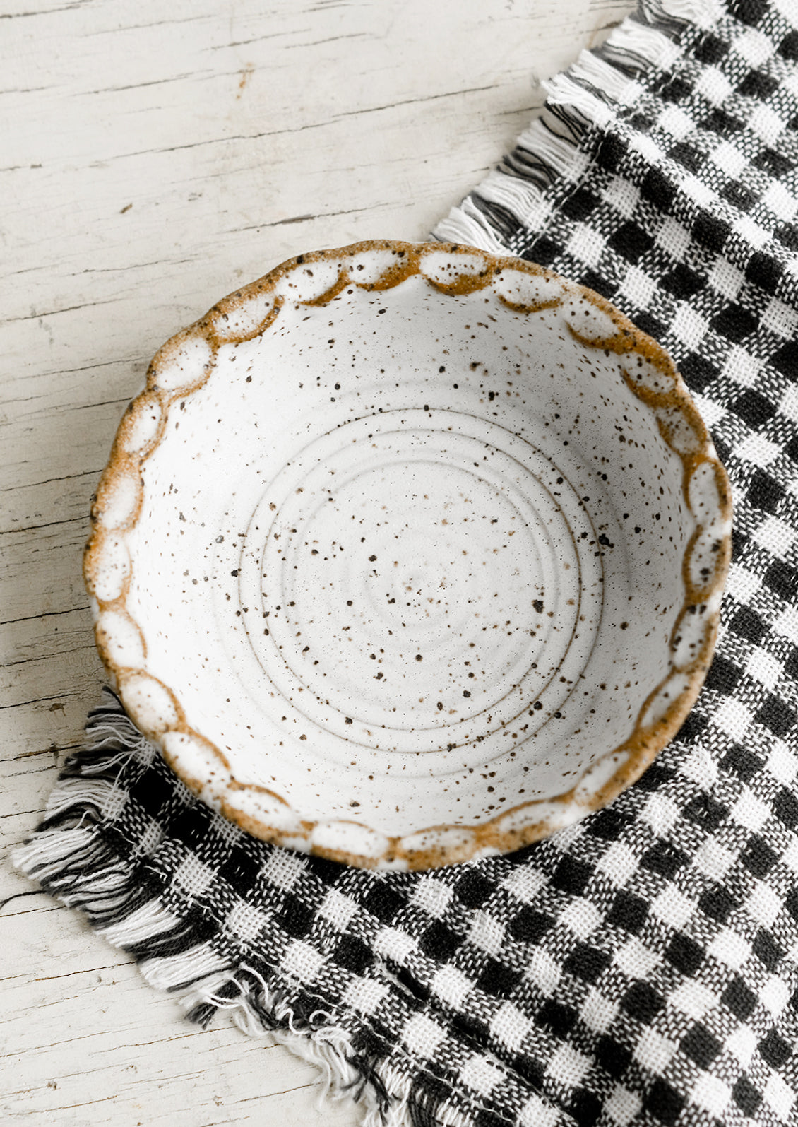 A small ceramic bowl with pinched rim in speckled white glaze.