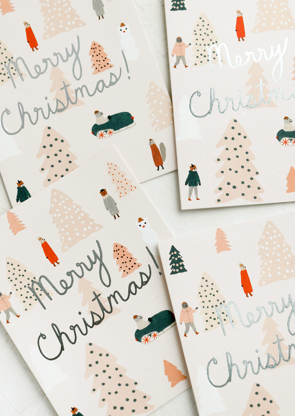 A greeting card set with animals surrounded by pink Christmas trees and silver text reads "Merry Christmas!".