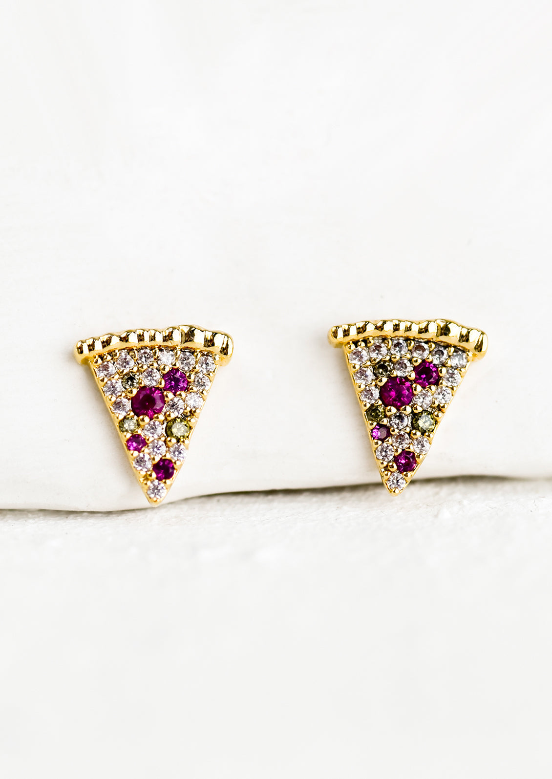 A pair of crystal and gold stud earrings in the shape of pizza slices.