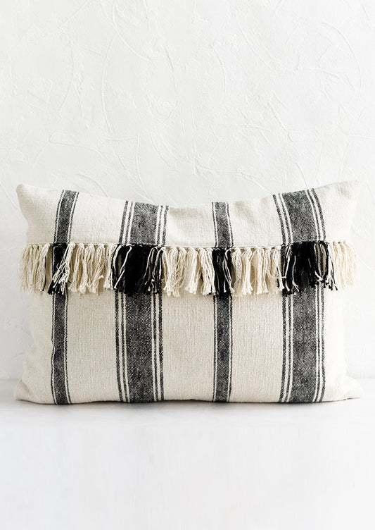 A lumbar throw pillow in natural cotton with vertical black stripes and horizontal fringe.