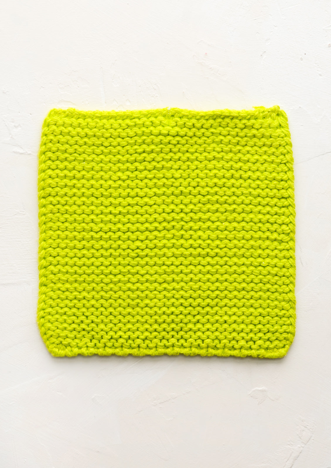 A square, chunky knit cotton potholder in lime green.