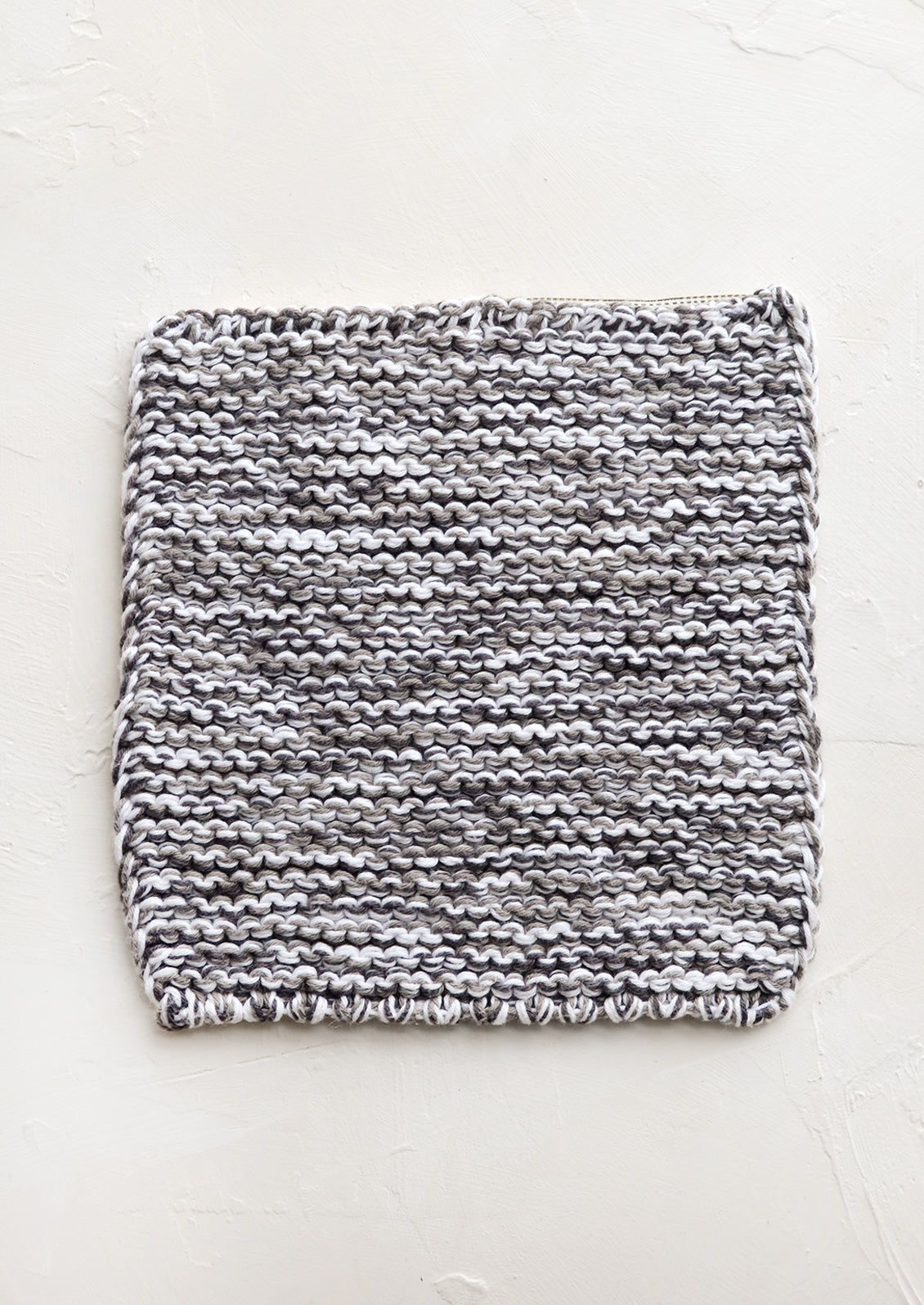 A square, chunky knit cotton potholder in black and white marl.