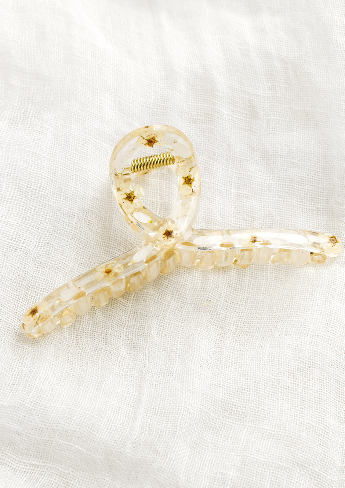 A clear crescent shaped hair claw with white dried flowers.