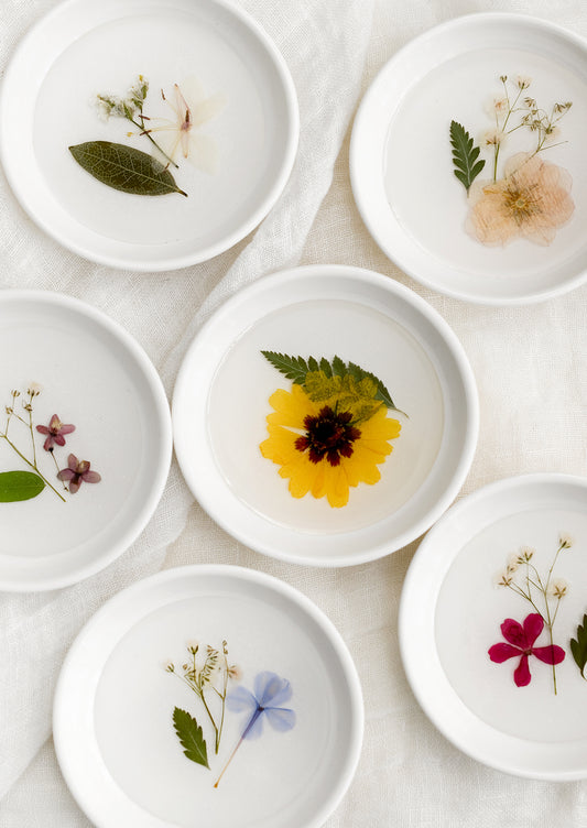 Assorted pressed flower ring dishes in white.