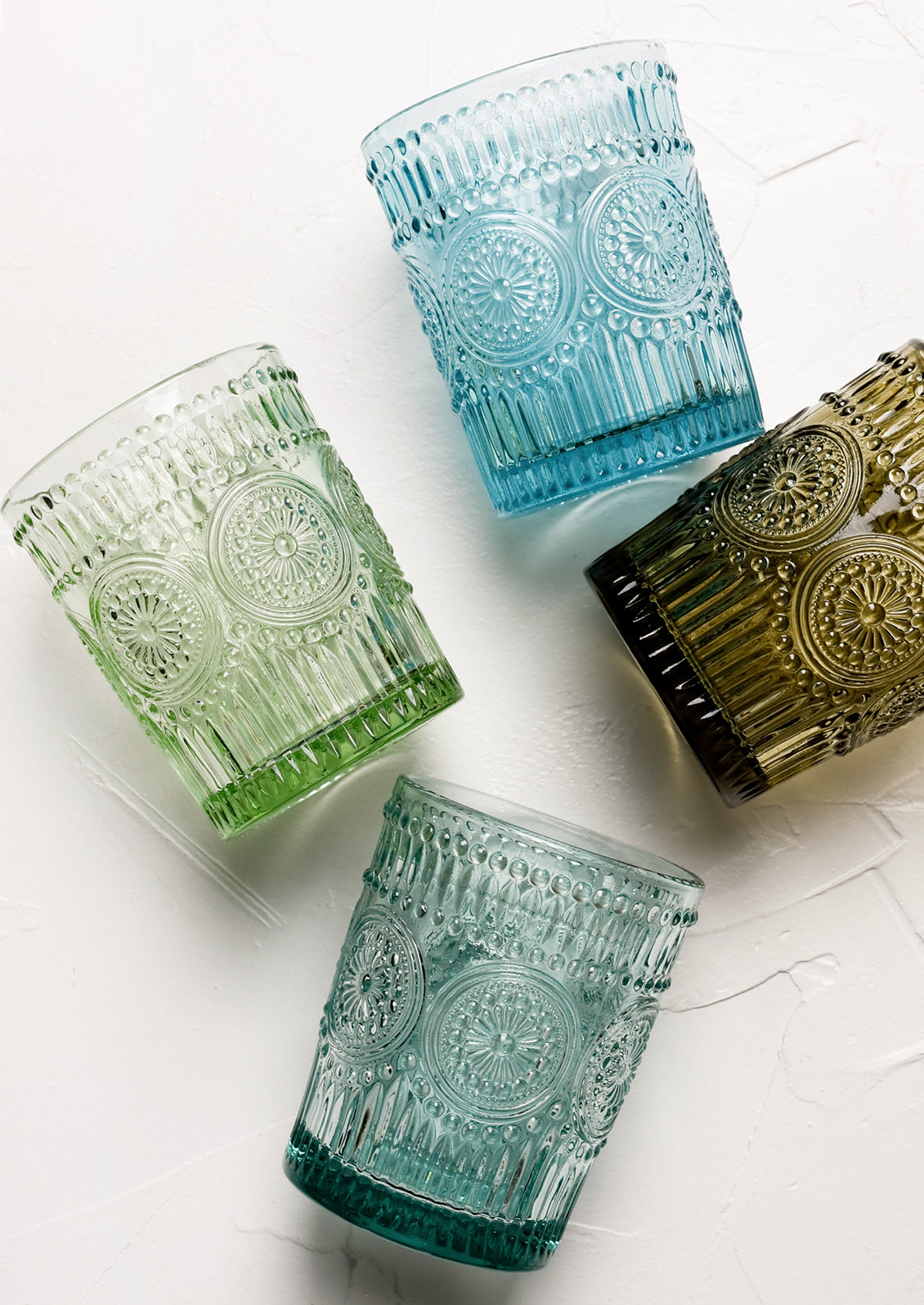 Glass cups in assorted blues and greens with Mexican inspired embossed medallion design.