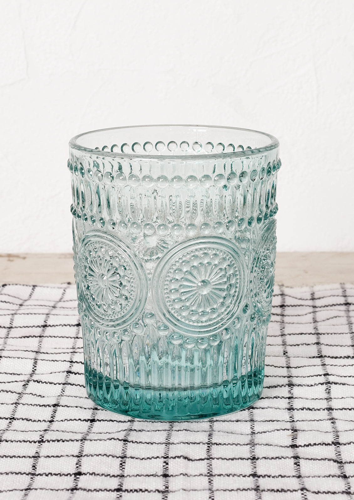 An aqua glass cup in embossed design.