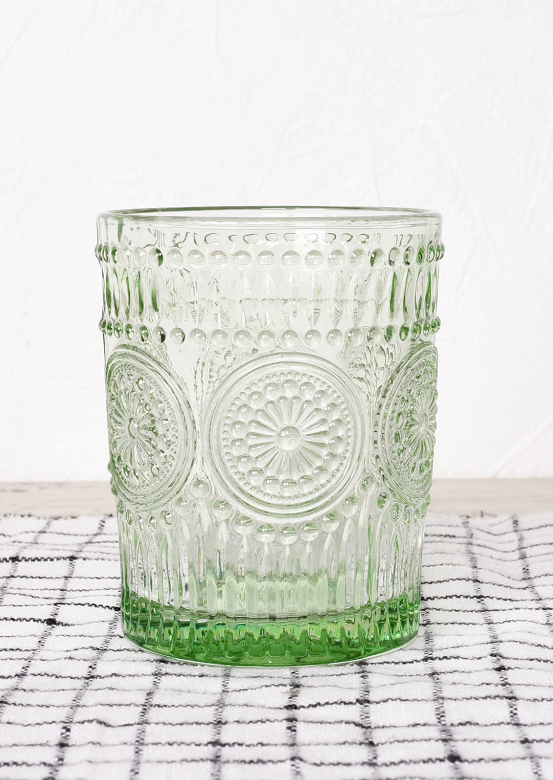 A green glass cup in embossed design.