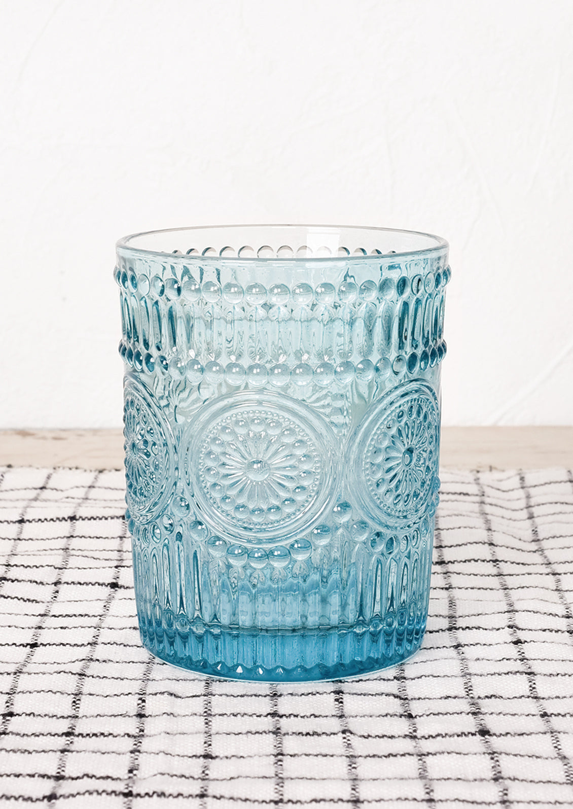 A turquoise glass cup in embossed design.