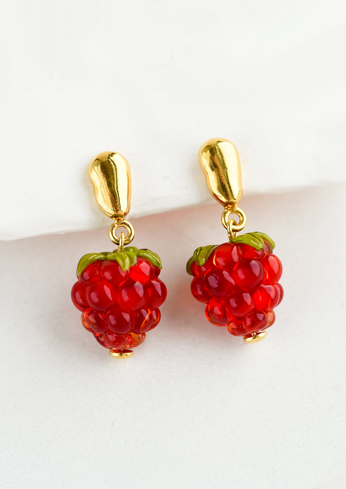 A pair of glass earrings in shape of raspberries.