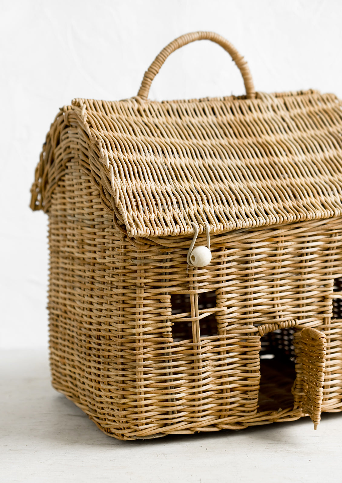 A rattan storage basket in the shape of a house.