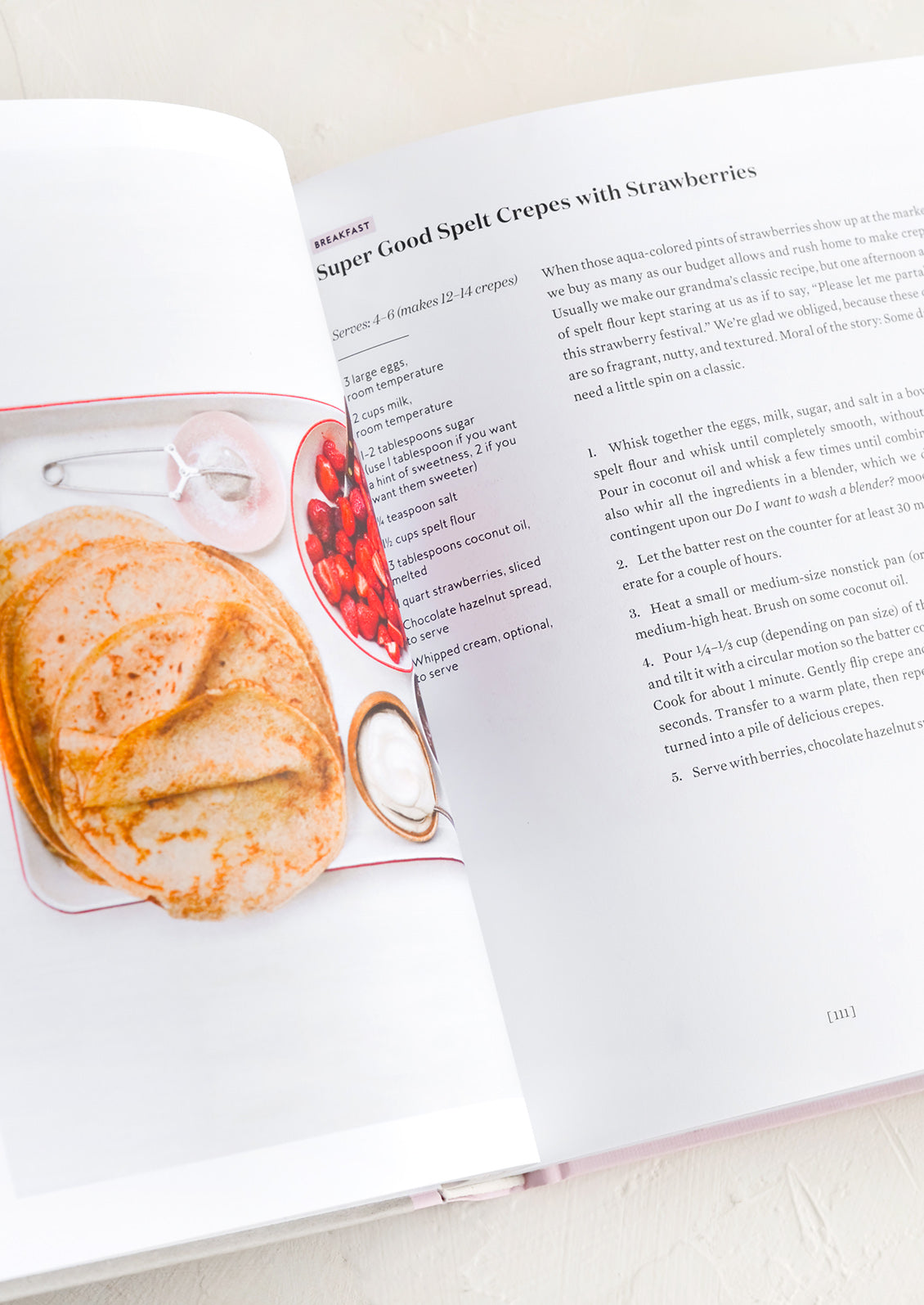 A cookbook open to recipe for spelt crepes with strawberries.