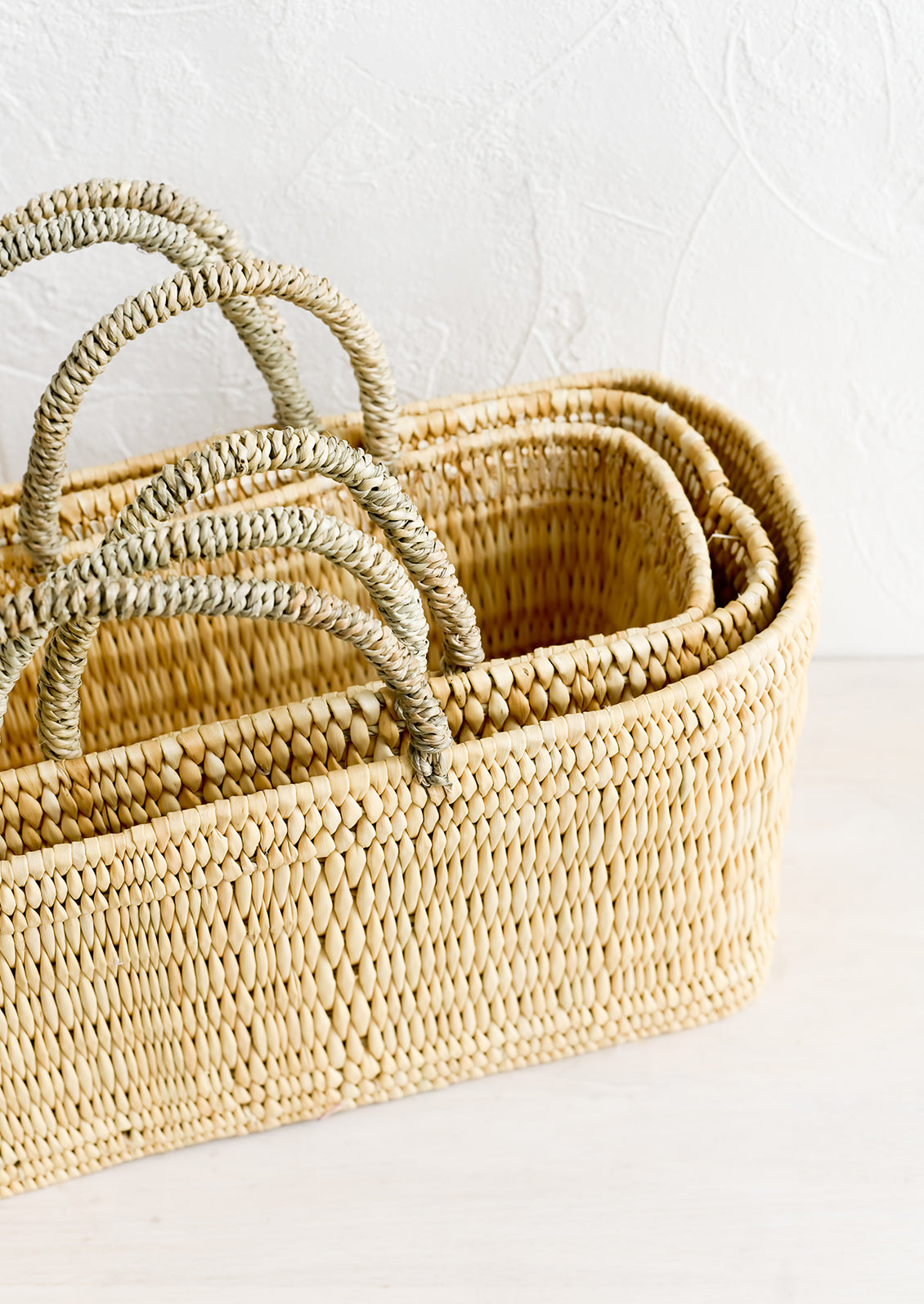 Nesting rectangular storage baskets with top handles.