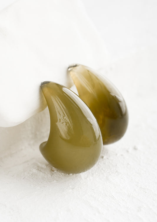 A pair of teardrop shaped resin earrings with curved bottom.