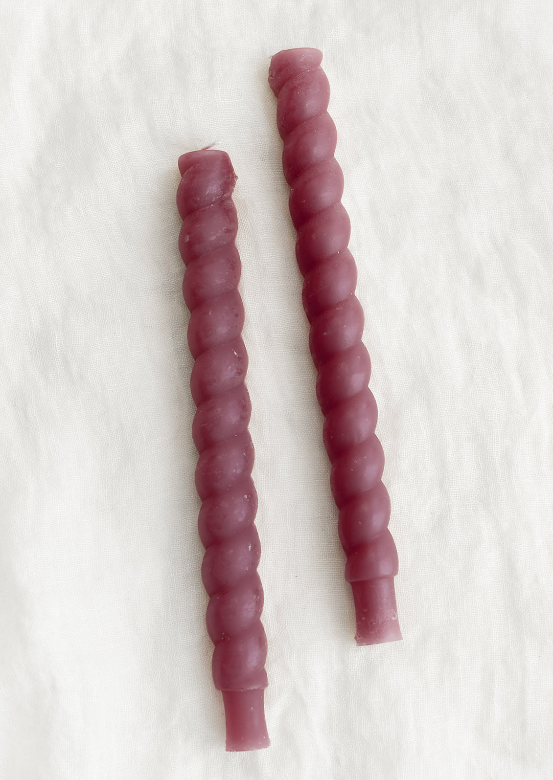 Two twisted taper candles in boysenberry color.