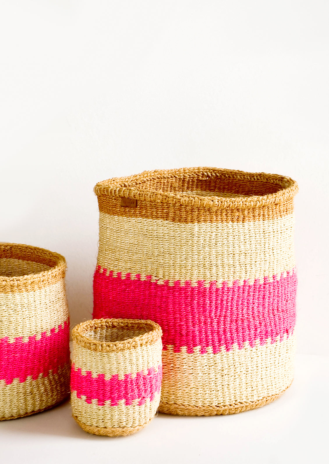 Woven sisal baskets in tan stripes with neon pink middle stripe