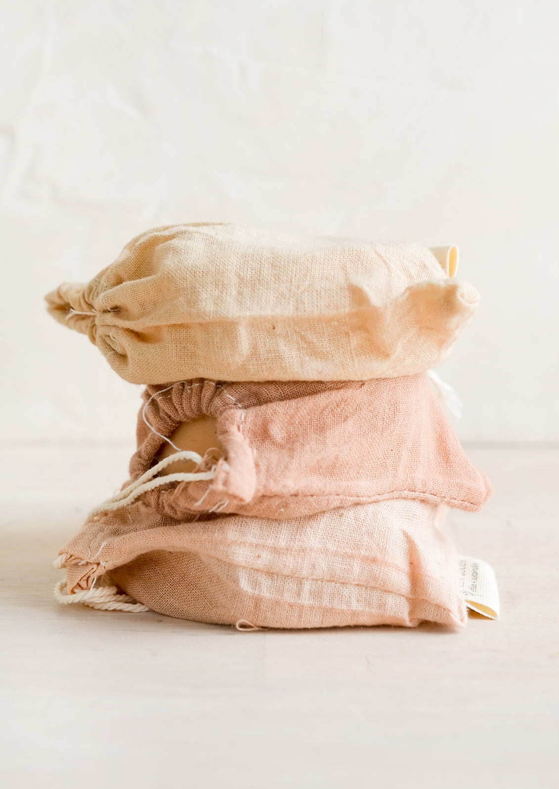 A stack of naturally dyed muslin pouches holding soap.