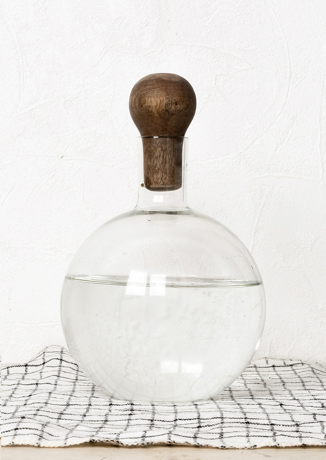 A glass decanter in round shape with dark wooden stopper.